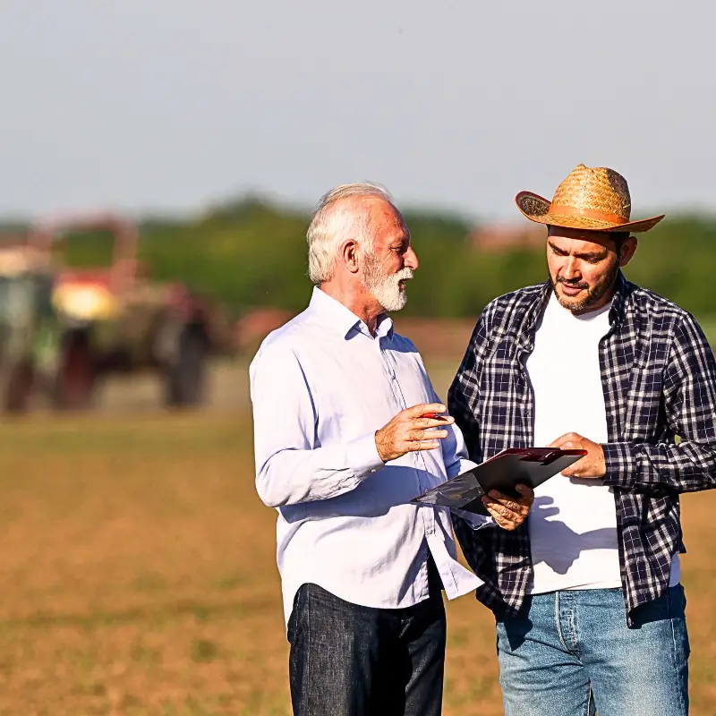 blockchain-farm-data-insurance-risk Farmer reviewing crop data on a digital device in the field, representing blockchain-based insurance risk solutions