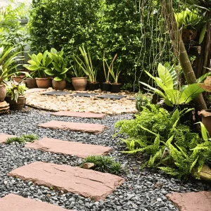 Stone and gravel garden pathway surrounded by potted plants and ferns, creating structure and flow in a small garden space