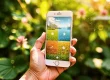 Hand holding a smartphone with a garden planning app interface, set against a lush green background—illustrating modern smart gardening gadgets.