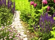 Stone garden path lined with tall purple spiked flowers and lush pink blooms—an inspiring example of space-saving garden path ideas.